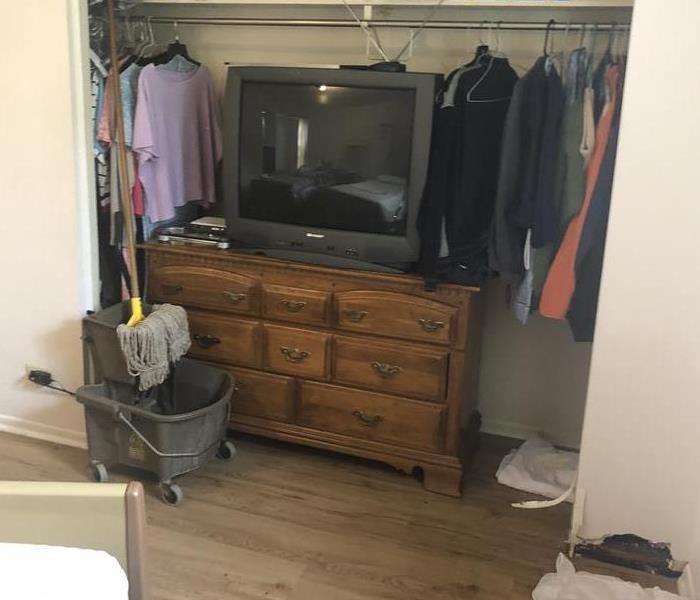 Bedroom closet with tv on a brown dresser and clothing