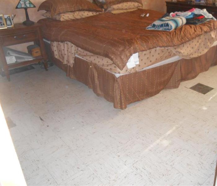 Master bedroom with bed (brown bedding) that shows the tile floor repaired