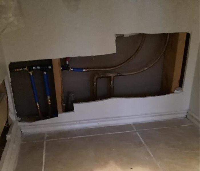 drywall removed in a home to expose damaged pipes