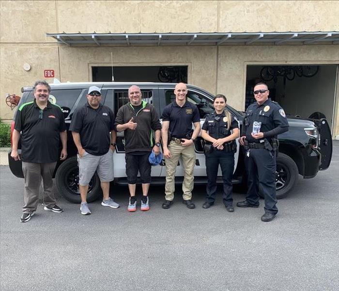 Two SERVPRO® of Alamo Heights techs stand with three Seguin Police officers in front of a Seguin police SUV