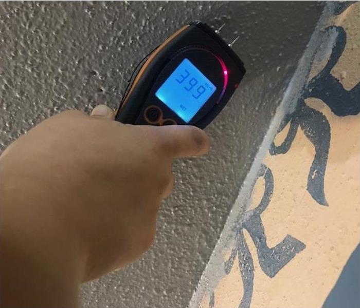 The meter indicates a digital reading of 39.9% in this piece of gray painted drywall.in Kirby, Texas