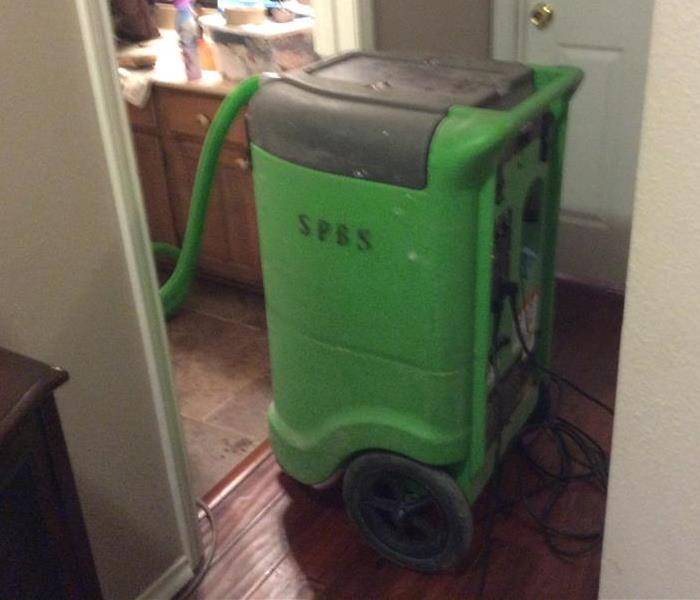 Green extractor in a hallway with hose in the bathroom
