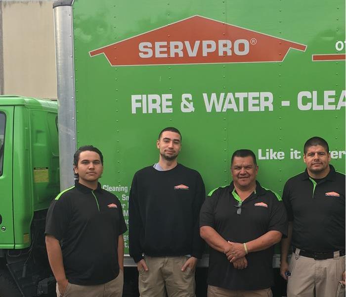 Four workmen in black shirts in front of a SERVPRO box truck 