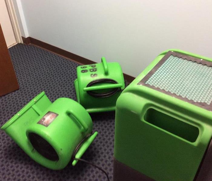 Two green air movers and a green dehumidifier in an office
