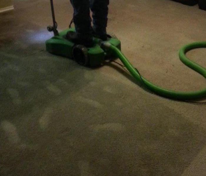 Man standing on extractor extracting water from a carpet