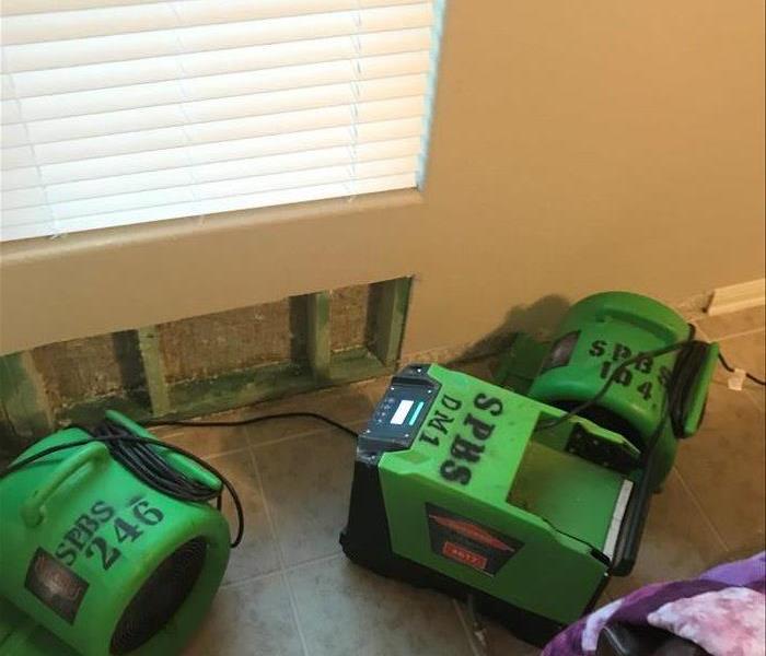 Three pieces of green drying equipment in a room that has a wall that has a flood cut 