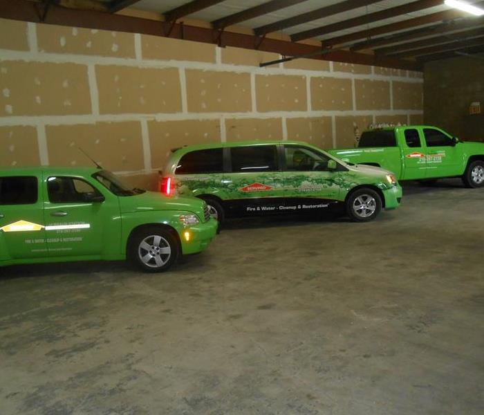 Three green vehicles in a warehouse