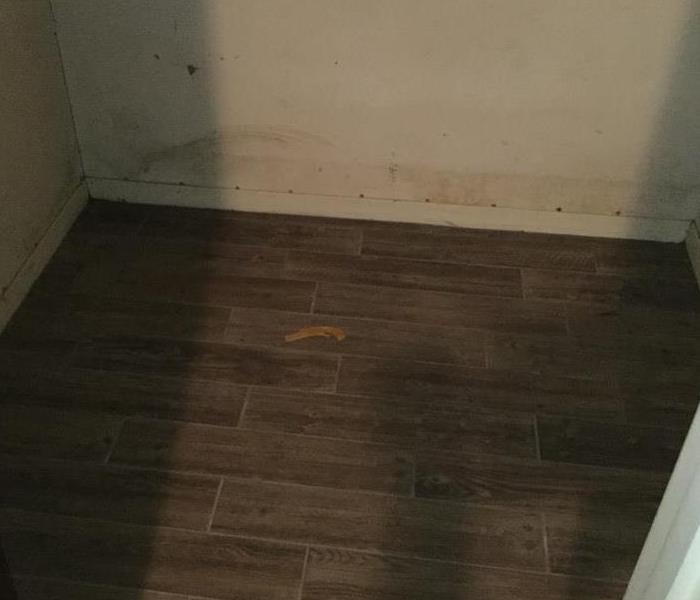Closet with brown hardwood dirty from water and wall dirty from flood water